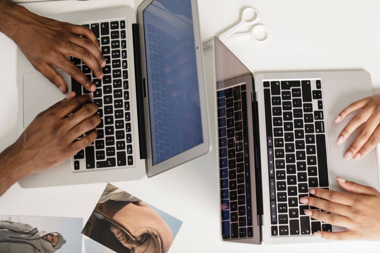 Mastering the First Impression: Your intriguing post title goes here Two hands typing on laptops on a white desk, viewed from above, fostering teamwork.